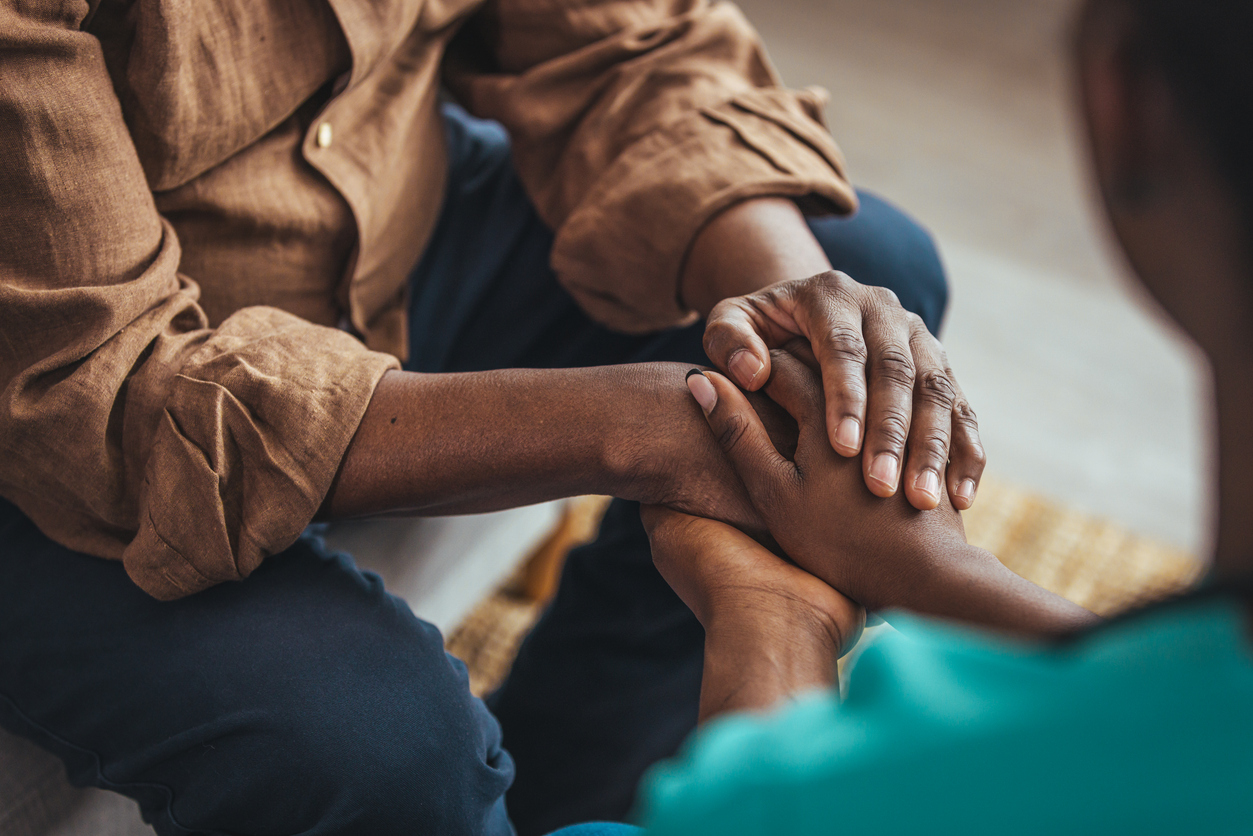 A caregiver holding the hand of an older adult
